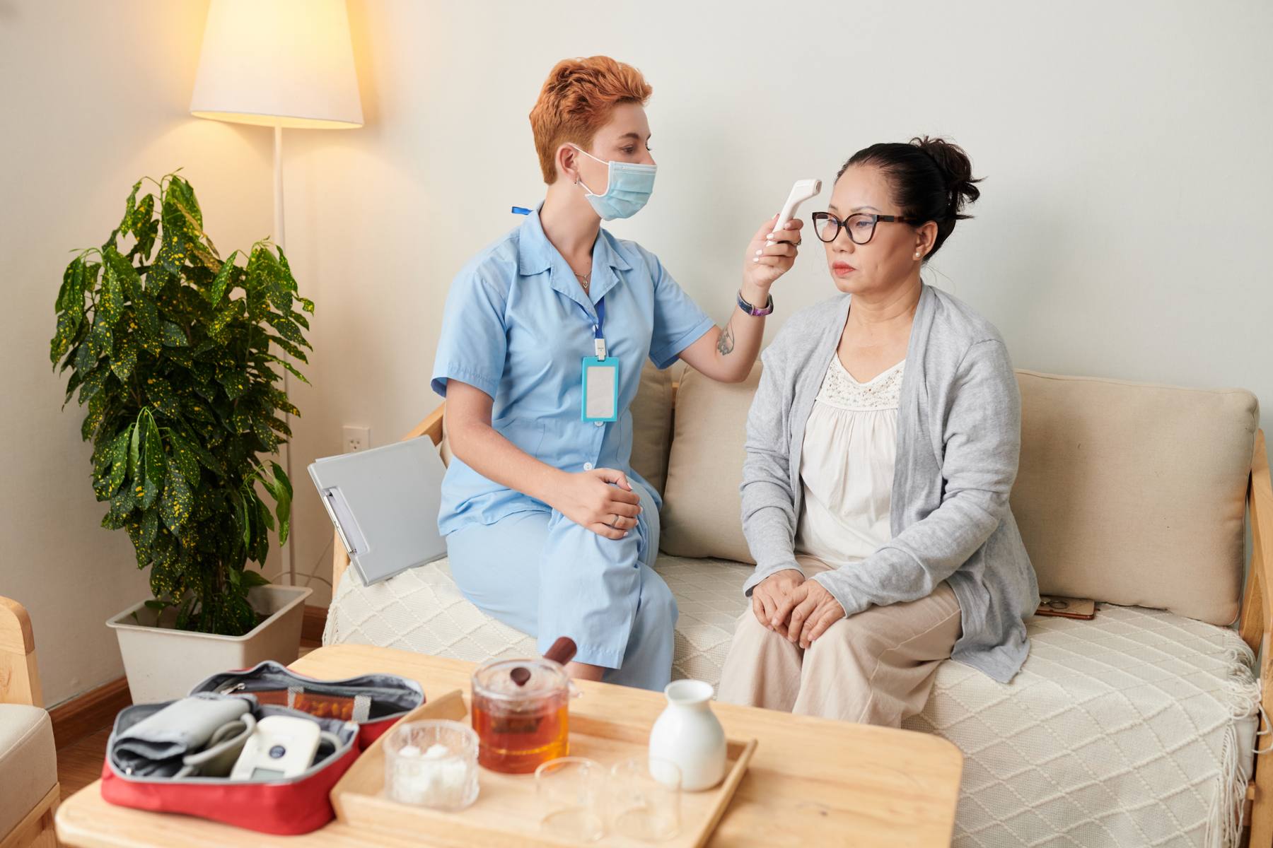 Nurse checking a client's temperature at home