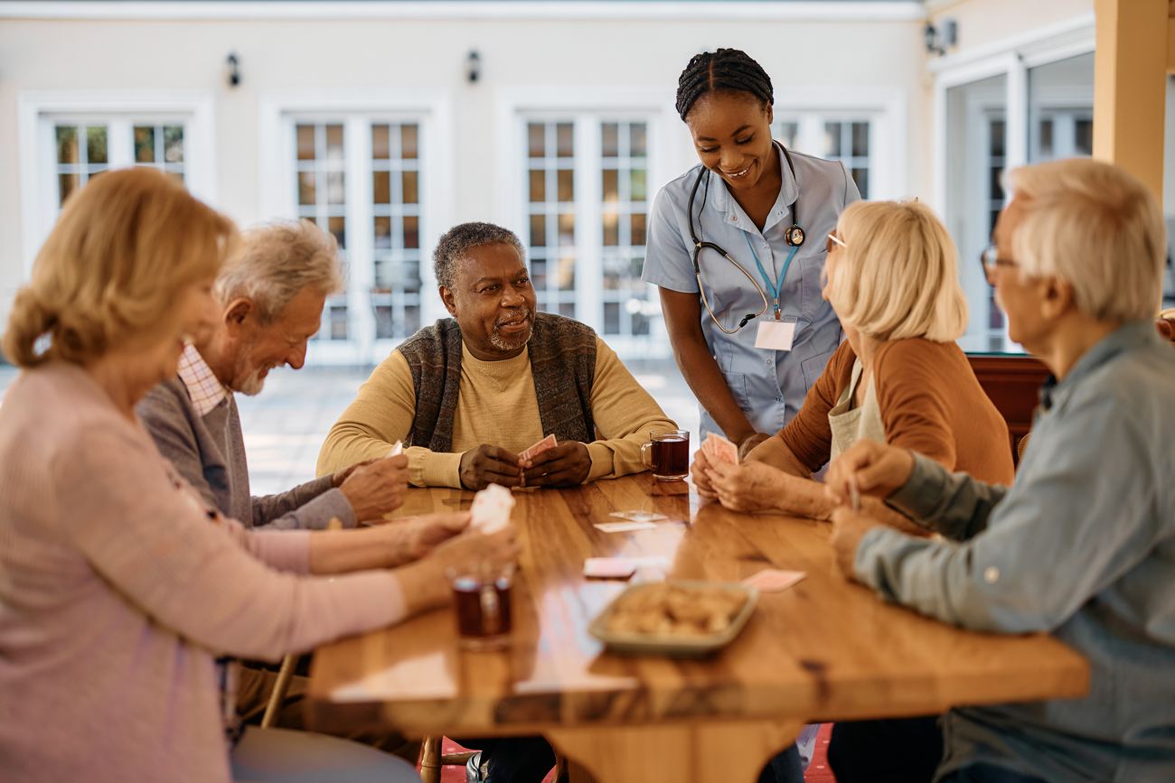 Residents playing cards outdoors with a carer